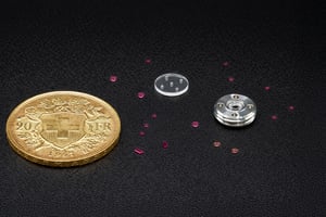 Precision sapphire micro discs and components displayed with a Swiss coin for scale, showcasing the accuracy of each custom sapphire part.