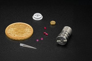 Assortment of precision micro components displayed next to a Swiss coin, each custom sapphire part shown to highlight scale and fine machining.