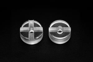 Top view of two circular custom sapphire parts featuring cross-shaped micro-machining and a central drilled hole.