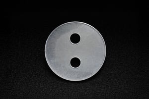 Flat circular custom sapphire part with two precision-drilled holes, displayed in macro detail.